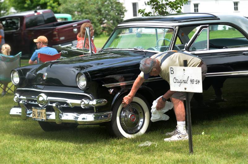 John Morris of Lyndon takes the hub cap off one of the wheels of his 1954 Ford Skyliner at the end of the Lyndon Car Show on Sunday, June 2, 2024.. John and his wife, Donna, live just a block away from Richmond Park, where the car show was held, but the hub cap tends to come off the wheel so John takes it off before hitting the road.