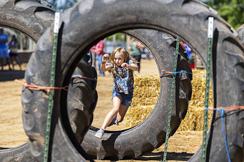 Annalee King, 8, of Thomson jumps through a tractor tire  Saturday, August 12, 2023 while competing in the the Carroll County Fair’s Ninja Farmer course. Kids ran, jumped, climbed and crawled through a series of obstacles while being timed.