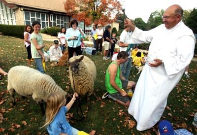 Shaw Local 2007 file photo – Deacon Jim Dombek of the Newman Catholic Student Center in DeKalb sprinkles holy water on Stomach and Shamrock, the sheep of Anna Butler, 10, of DeKalb (left), on Sunday afternoon during the annual Blessing of the Animals at the Newman Center.