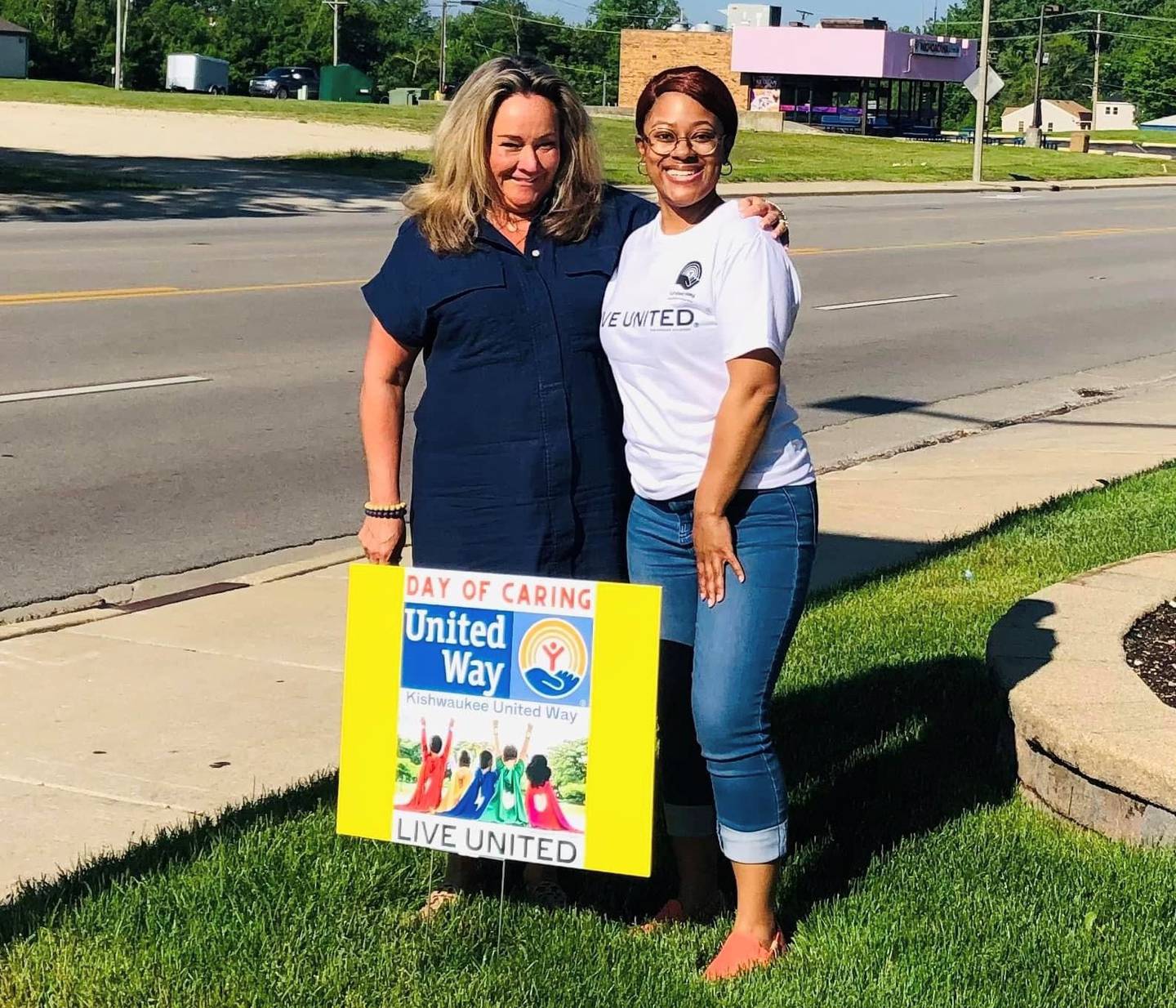 Mary Freeman of FNBO and Stacie Miller of Kishwaukee United Way post in front of a sign promoting the agency's annual Day of Caring, this year set for 9 a.m. June 13, 2024.