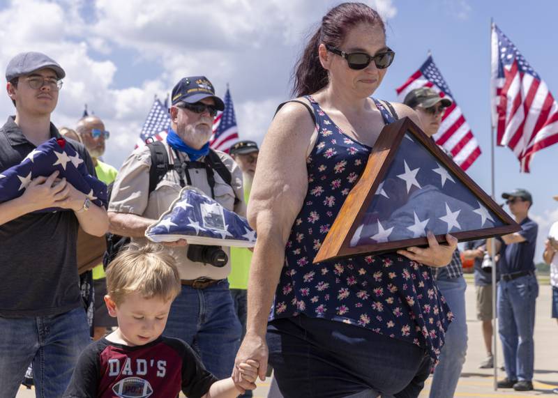 Christy Hines and her son Elijah walks in the parade with a folded flag of a loved one during the TBM Avenger Reunion and Salute To The Veterans at Illinois Valley Regional Airport on May 18, 2024.