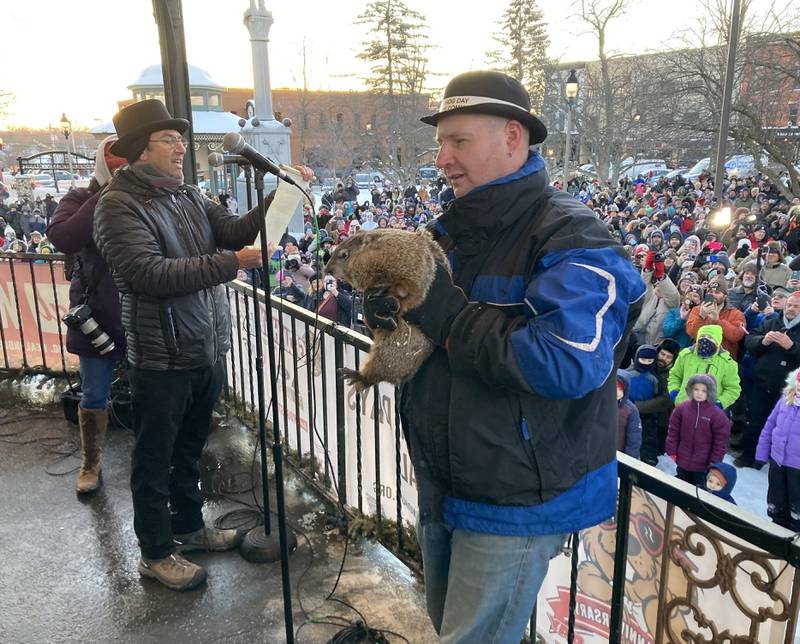 Woodstock Willie is held by handler Mark Szafran as Willie makes his prognostication of six more weeks of winter on Thursday, Feb. 2, 2023, as Danny Rubin, the screenwriter of the “Groundhog Day” movie filmed in Woodstock, announces Willie’s findings during the annual Groundhog Day Prognostication on the Woodstock Square.