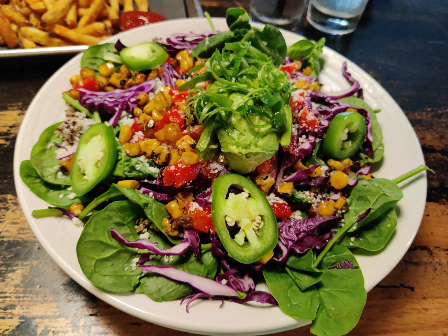 The elote power bowl. The colorful dish was superlative, with delicious grilled corn paired with red cabbage, red pepper, green onion, quinoa, Cotija cheese, avocado, fresh spinach leaves and slices of jalapeño. It normally is served with chili wasabi ranch, at The GOAT burger + cocktail bar in Batavia