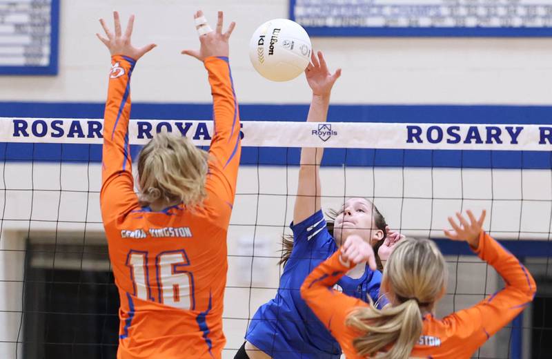 Rosary's Sarah Schmidt spikes the ball between two Genoa-Kingston players during their Regional semifinal match Tuesday, Oct. 25, 2022, at Rosary High School in Aurora