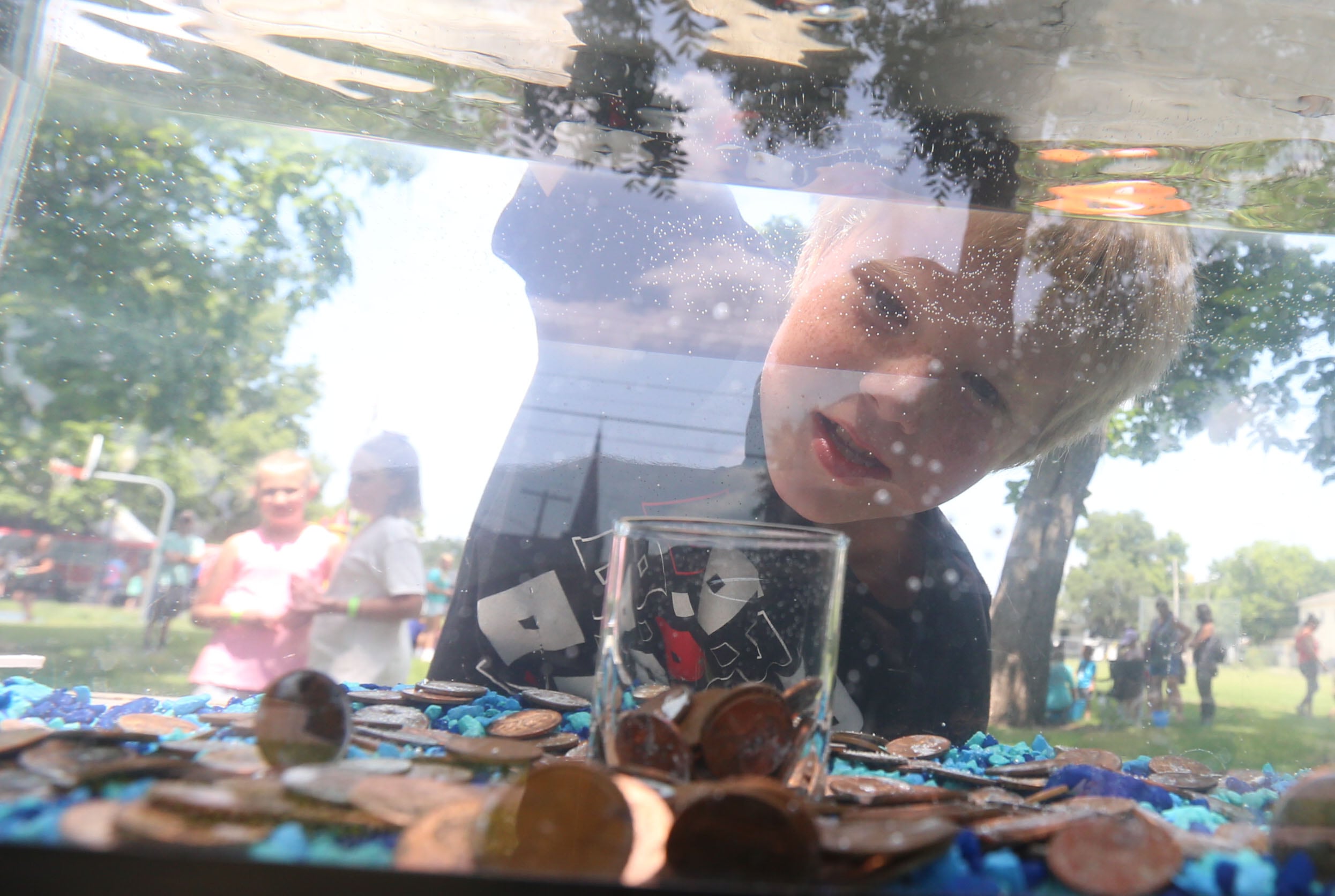 Grayson Gray tries his luck while attempting to drop a penny into a glass in water during the Ottawa Recreation Summer Carnival on Wednesday, July 25, 2024 at Rigden Park in Ottawa. The carnival featured games, activities, bounce houses, and more. It wa the last event of the season.