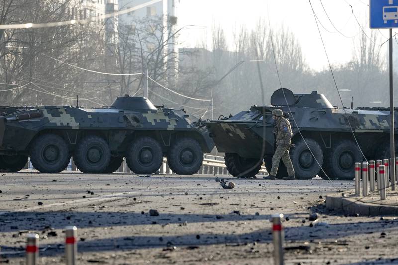 A soldier walks along Ukrainian armored vehicles blocking a street in Kyiv, Ukraine, Saturday, Feb. 26, 2022. Russian troops stormed toward Ukraine's capital Saturday, and street fighting broke out as city officials urged residents to take shelter. (AP Photo/Efrem Lukatsky)