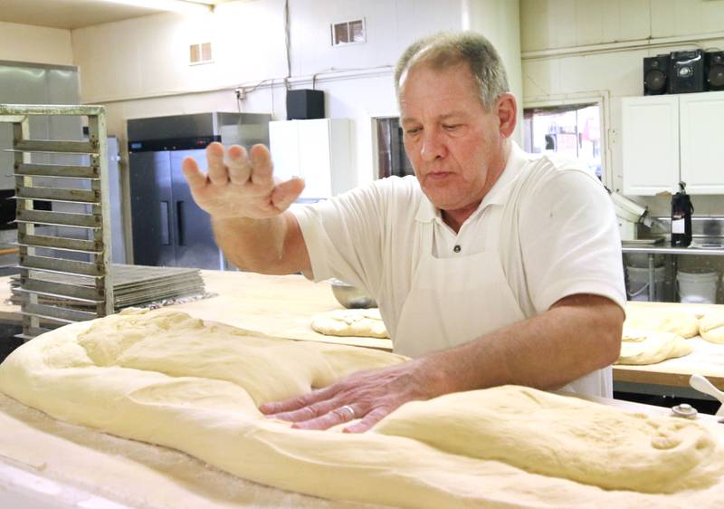 Ken Elleson, owner of Elleson's Bakery, flattens the dough before it is sliced up for paczkis Monday, Feb. 28, 2022, in the kitchen of the bakery in Sycamore. Elleson and members of his family will be working all night making the paczkis from scratch to be ready at 5 a.m. tomorrow for Fat Tuesday.