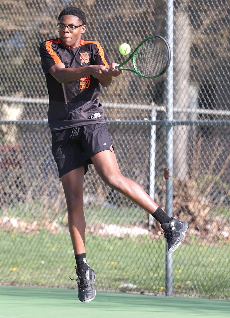 DeKalb number one doubles player Matthew Williams jumps and hits a backhand Wednesday, April 26, 2023, during their match at Sycamore High School.