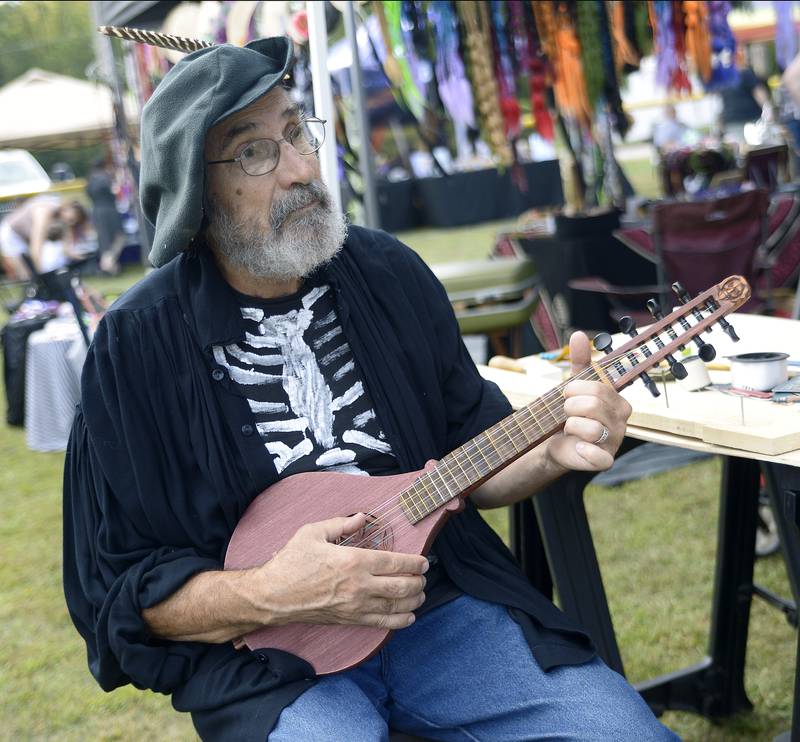 Glenn Brown from his vendor booth, performs on a Cittern on Saturday, Sept. 14, 2024, that he crafted. Many vendors were available selling a variety of crafts during the Marseilles Renaissance Faire.