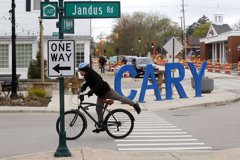 A man gets onto his bicycle and the intersection of Jandus Road and West Main Street in Cary on Tuesday, April 25, 2023. The village of Cary is considering a new tax increment financing district in its downtown corridor to help spur new development in the oldest part of its town.