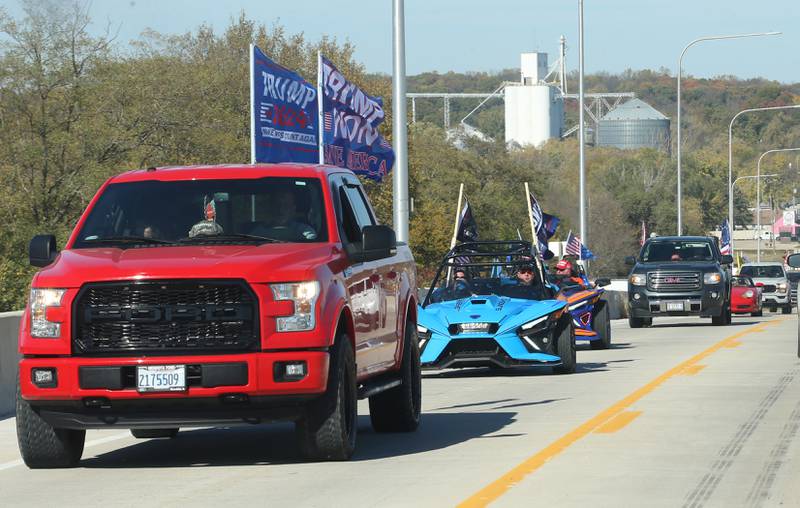 A pickup truck waves Trump 2024 flags while leading others in the Trump Caravan over the Illinois Route 178 on Saturday, Oct. 19, 2024 in Utica.