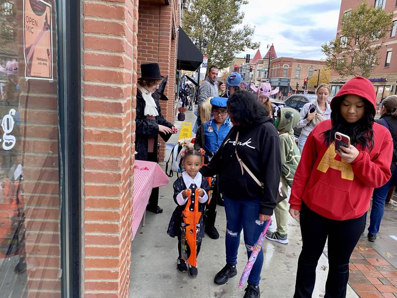 (Left) Serenity Medina, 4, dressed as Wednesday Addams from the franchise "The Addams Family" got her fill of candy joined by Brooklyn Lazcano, 9, dressed as a police officer in downtown DeKalb Thursday, Oct. 26, 2023 for the 26th annual Spooktacular hosted by the DeKalb Chamber of Commerce.