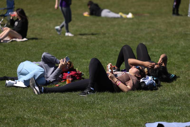 A group lays in the grass to view the eclipse at the Joliet Junior College solar eclipse viewing event on Monday, April 8, 2024 in Joliet.
