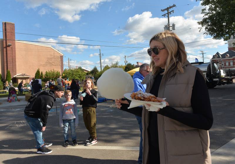 Kate Kastanova of Oregon holds a funnel cake and cotton candy as she walks by the Fun Zone during Autumn on Parade on Saturday, Oct. 7, 2023.