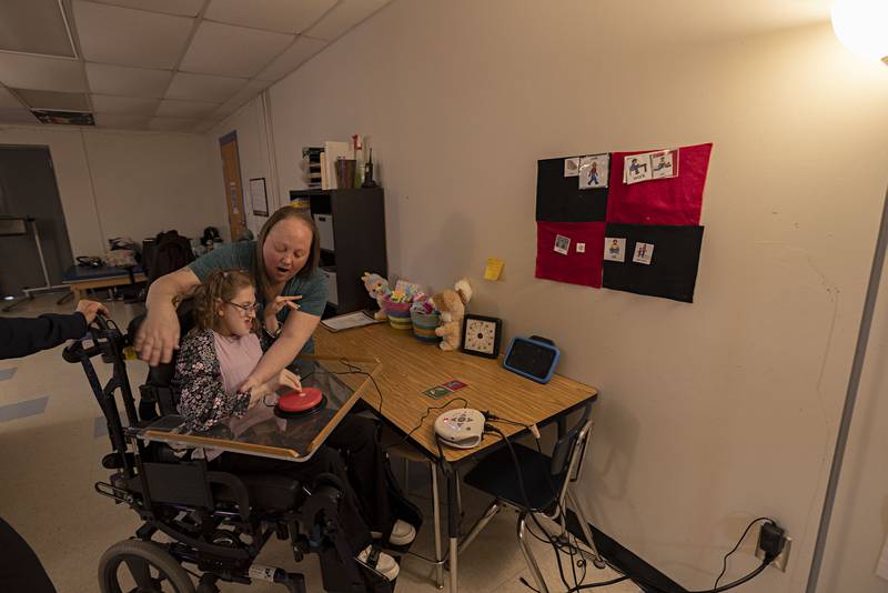 One to one paraprofessional Sherryl Surrena works with student Addy Weidman with a switch to control a light Thursday, April 6, 2023 at Reagan Middle School.