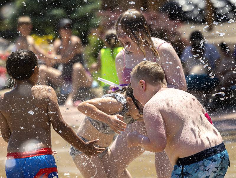 Children play in the cooling water raining down Wednesday, June 12, 2024 at the Dixon Parks District splash pad.