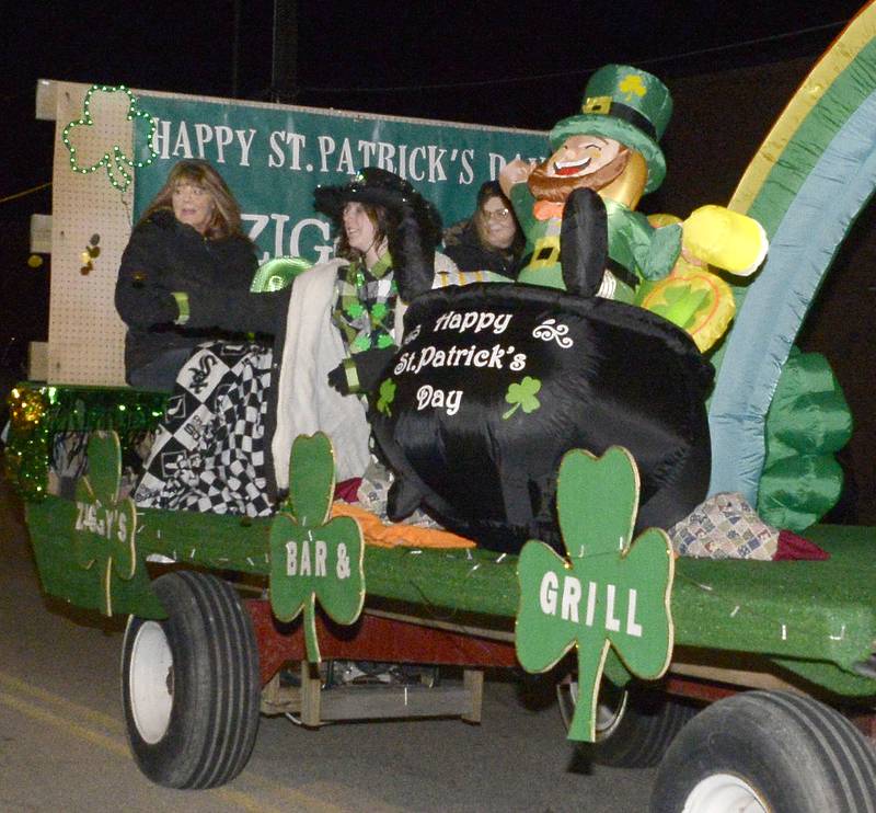 Riders in the Ziggy’s Bar & Grill float toss out treats Saturday, March 11, 2023, to those along Main Street during the Marseilles St. Patrick’s Lighted Parade.