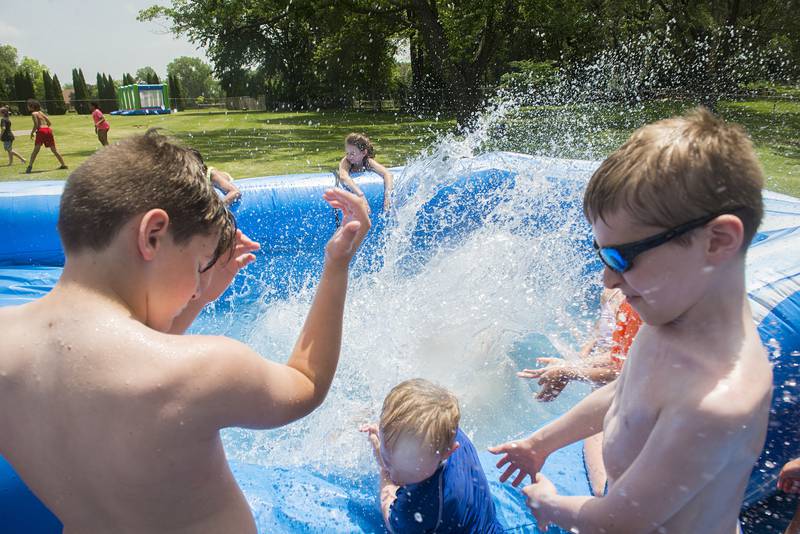 During Dixon Park Districts' SPARK camp, onlookers get splashed Wednesday as a friend finishes their ride down the water slid in the pool.