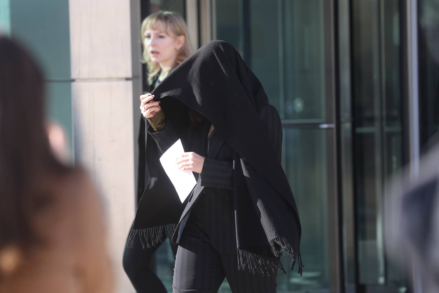 Kyleigh Cleveland-Singleton, 21, shrouds her face with a scarf as she exits the Will County Courthouse on Thursday, Feb. 8, 2024 in Joliet. She is charged with obstructing justice in the investigation and apprehension of her boyfriend, Romeo Nance, 23, whom police say was a suspect in the Jan. 21 mass shooting in Joliet.