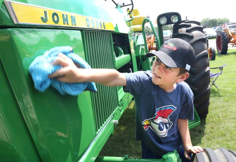 Eli Todd, 10, from Waterman, shines up his grandpa’s 1967 John Deere 4020 tractor on display Saturday, July 15, 2023, at the Waterman Lions Summerfest and Antique Tractor and Truck Show at Waterman Lions Club Park.