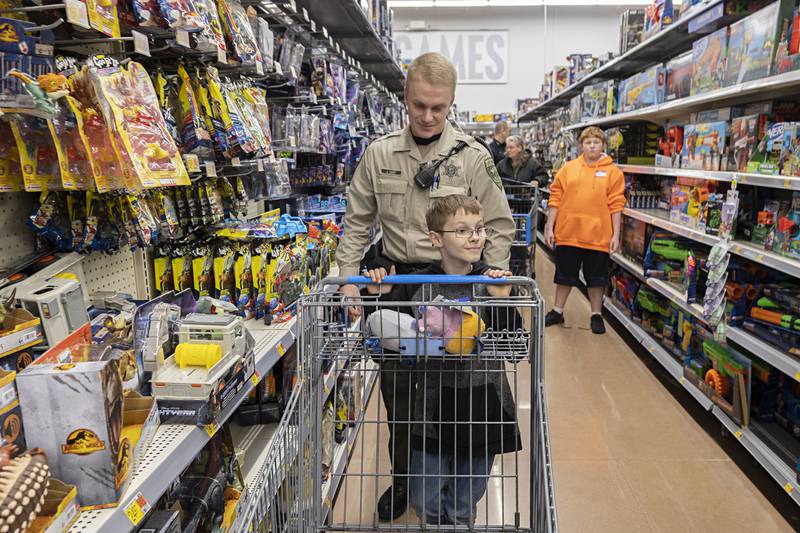 Lee County deputy Justin Hart picks out items with Kalob Bonnell, 10, Saturday, Dec. 10, 2022 in Dixon.