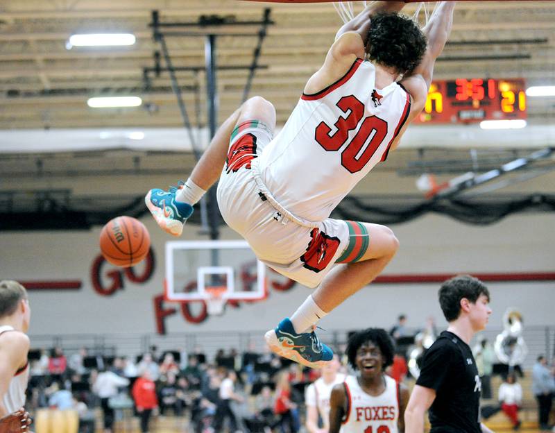 Yorkville's Bryce Salek (30) hangs on the rim after a slam dunk after he recovered his own three-point miss against Oswego East, during a varsity basketball game at Yorkville High School on Friday, Feb. 9, 2024.