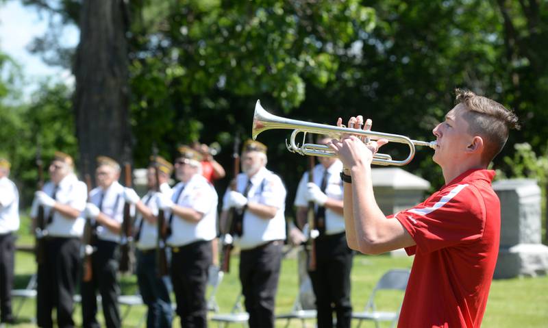 Oregon High School band member Gavyn McArthur plays taps as seven veterans stand at attention during the Memorial Day service at Riverside Cemetery in Oregon on Monday, May 27, 2024. Band member Isaac Ebert, seen behind the veterans, echoed the song with McArthur.