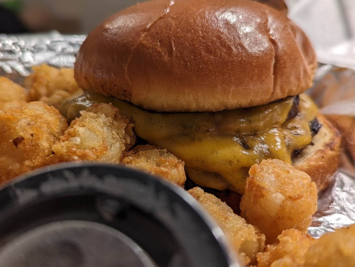 Pictured is the cheddar brat burger with tater tots as served at Craft'd Plainfield.