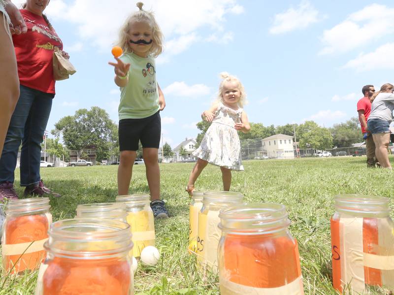 Teddy Chapman and his sister Lilly throw ping pong balls into mason jars during the Ottawa Recreation Summer Carnival on Wednesday, July 25, 2024 at Rigden Park in Ottawa. The carnival featured games, activities, bounce houses, and more. It wa the last event of the season.