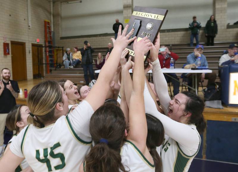 Members of the St. Bede girls basketball team hoist the Class 1A Regional plaque after defeating Amboy on Friday, Feb. 16, 2024 at Marquette High School.