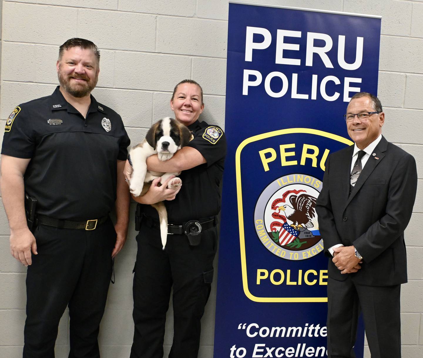 School Resource Officer Brian Zebron with Peru Police Chief Sarah Raymond holding  Peru's newest recruit Haven and La Salle State's Attorney Joe Navarro.