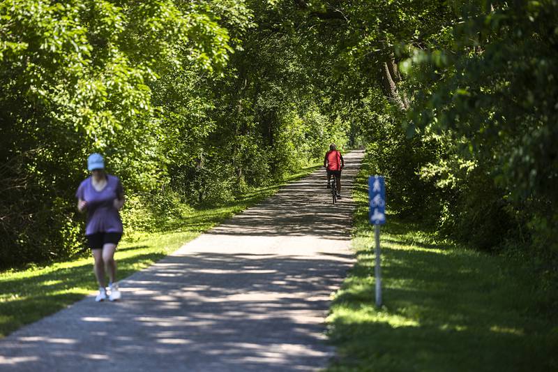 Riders and runners use the Lowell Parkway trail Wednesday, June 12, 2024 near The Meadows. The park district has been working to enhance the trails for comfort and safety.