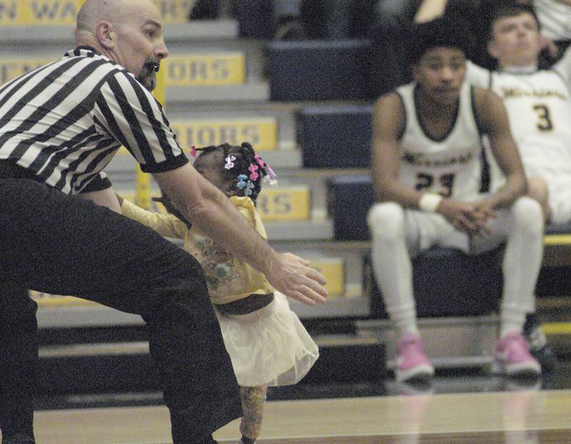 Referee Paul Tipton scoops up a loose child while keeping the eye on action  during Sterling’s 3A Regional semifinal game Wednesday, Feb. 21, 2024, at Sterling High School.