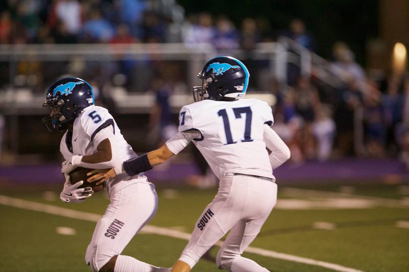 Downers Grove South's Dominic West hands the ball off to Kayden Smith against Downers Grove North on Friday Sept. 6,2024 in Downers Grove.