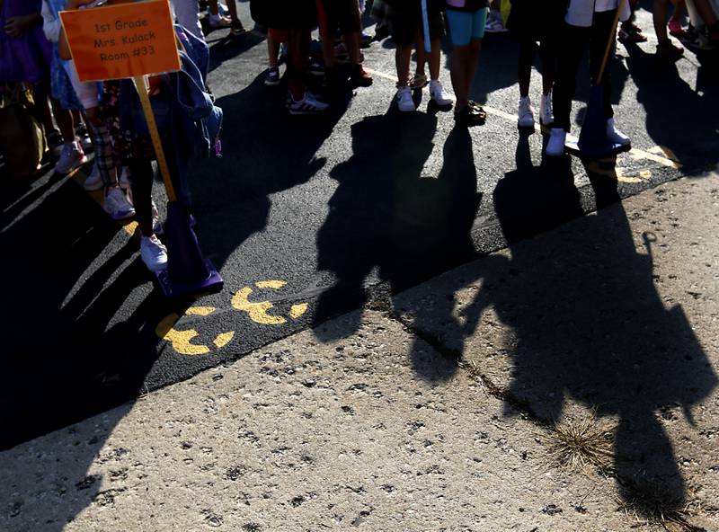 Students cast long shadows as they wait for school to begin on Wednesday, Aug. 21, 2024, at Coventry Elementary School in Crystal Lake.