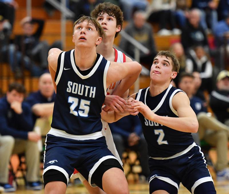 Downers Grove South's Daniel Sveiteris (25) and 
Will Potter (2) block out Batavia's Jax Abalos as the three watch for a rebound. during a Jack Tosh Classic game on Dec. 26, 2023 at York High School in Elmhurst.