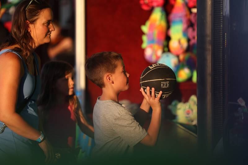 Matthew Funke takes a shot at a carnival game as his mother Chrissy and sister Grace watch at the Taste of Joliet on Friday, June 21, 2024 at Joliet Memorial Stadium.