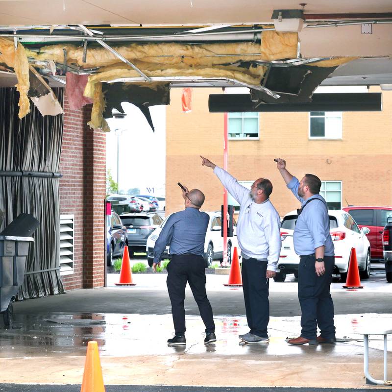 Northwestern Medicine Valley West Hospital employees inspect the damage in the ambulance bay after a truck too tall for the clearance tried to drive through it Tuesday, May 7, 2024, at the hospital in Sandwich. There was visible damage to the ceiling of the bay with insulation a wall material hanging down.