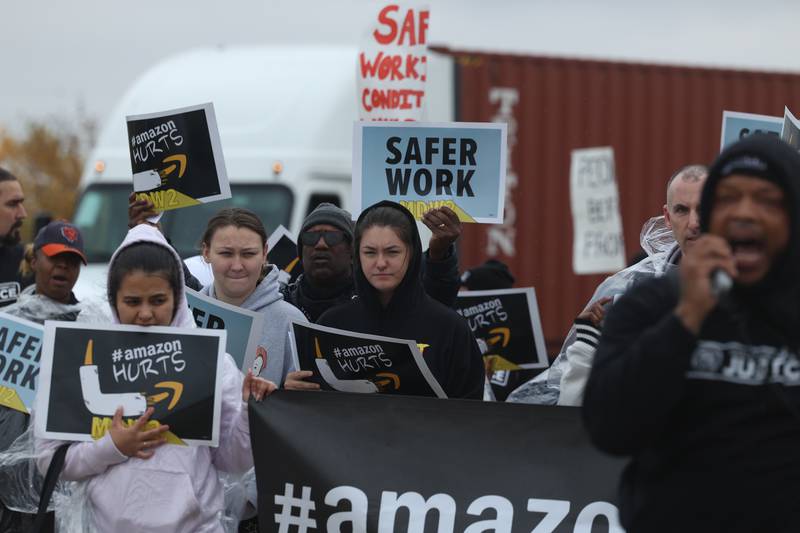 A truck navigates around protesters as they walk along Emerald Drive during a staged walkout at Amazon’s MDW2 facility. Amazon employees of MDW2 are teaming with Workers for Justice, a nonprofit organization supporting warehouse workers, to demand a safer work place and jobs that offer a living wage.