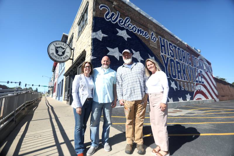 (Left to right) Building owners Keri and Jason Pesola of Yorkville, artist Joshua Schultz of Oswego and PMG Creative Director Cami Lorentsen in front of Yorkville’s newest mural on the north side of Crusade Burger Bar at 209 S Bridge St. in downtown Yorkville.