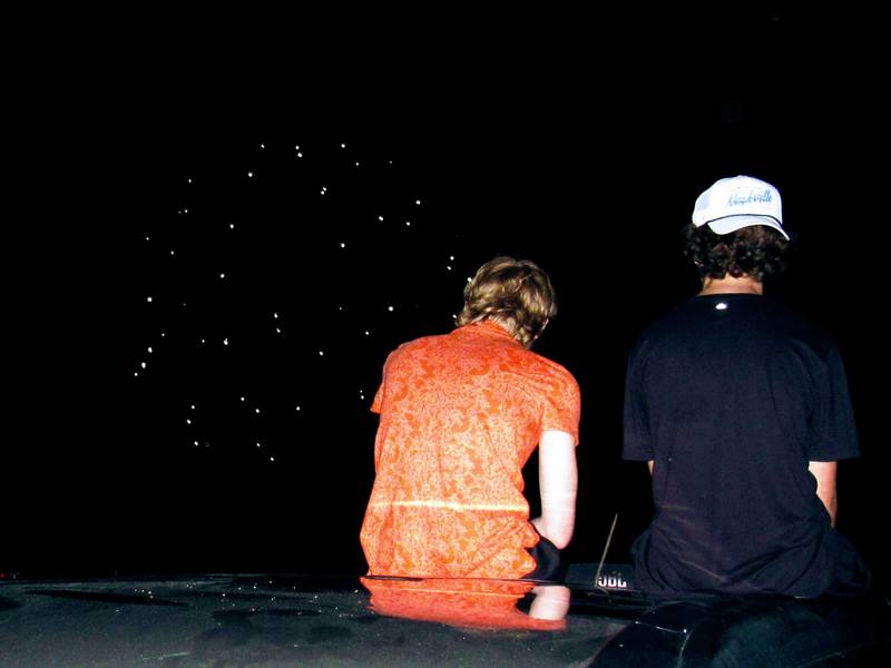 Blaine Elder-Miller and Tom Cullen watch the fireworks while sitting on top of a car in the Grundy County Fairgrounds parking lot.