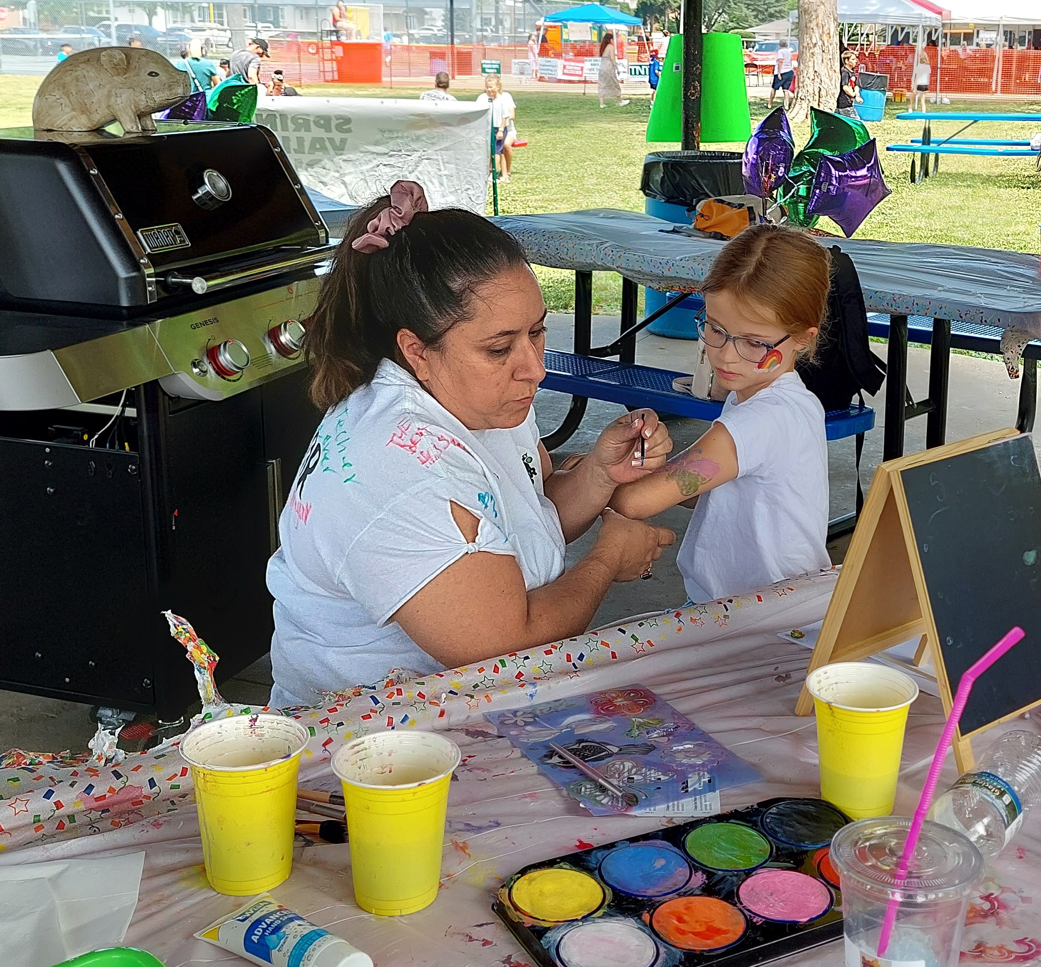 Mia Spanos, of Spring Valley, gets her arm painted Saturday, June 10, 2023, during Summerfest at Kirby Park in Spring Valley.