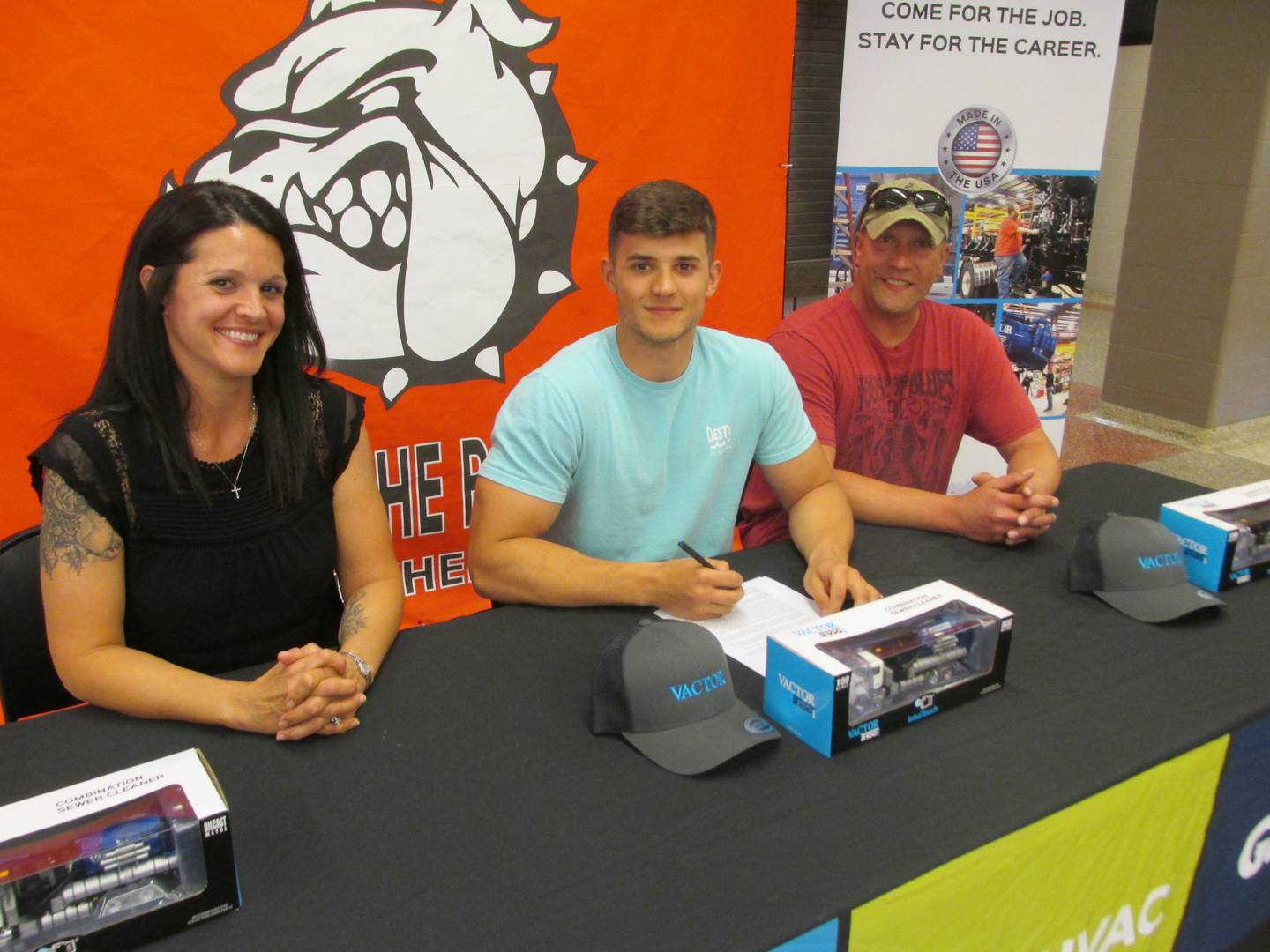 Streator High School student Chase Hamara accepts a full-time position at Vactor Manufacturing during a signing day event Thursday, May 11, 2023. Joining him are his parents Lindsay Tincher and Jim Hamara.