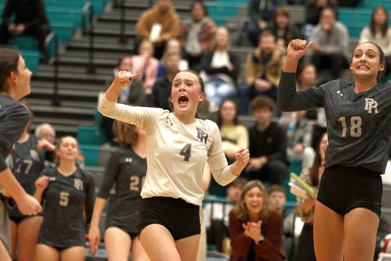 Prairie Ridge’s Alli Rogers, center, and Maizy Agnello, right,celebrate a point against Woodstock in IHSA Class 3A sectional semifinal volleyball action at Woodstock North Monday.