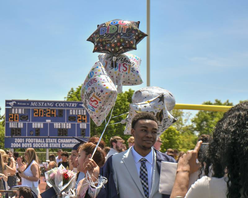 Lashay Rucker takes a photo of her son Trevon Williams after the Downers Grove South graduation ceremony that took place at Downers Grove South High School on Sunday May 19, 2024.