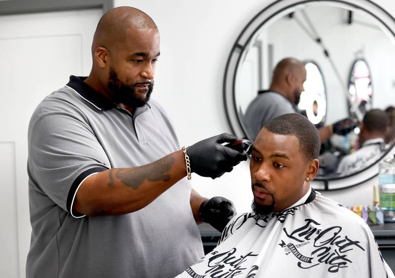 Julian McElroy gets a haircut from Andre Powell, owner of In & Out Cuts Barbershop, Friday, Aug 9, 2024, in the barbershop’s new location at 2331 Sycamore Road in DeKalb.