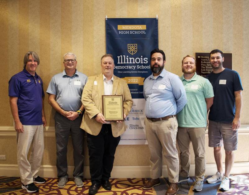 (from left to right) Matt Gehm, Joe Masini, Jason Artman, Dan Beck, Joseph Hughes and Eric Straughn accept the Democracy School Network banner at a conference in Lisle on Sept. 15, 2022.