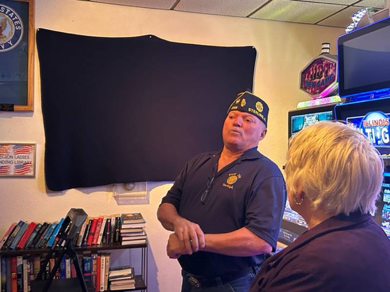 Sterling American Legion Post Commander Nelson Vasquez speaks prior to the unveiling of a picture titled "Last Stop Before Home" at the Legion on Saturday. In the foreground is Freida McCombs, whose late husband, Robert, wanted the picture hung at the Legion to honor and remember those who didn't make it home from war.