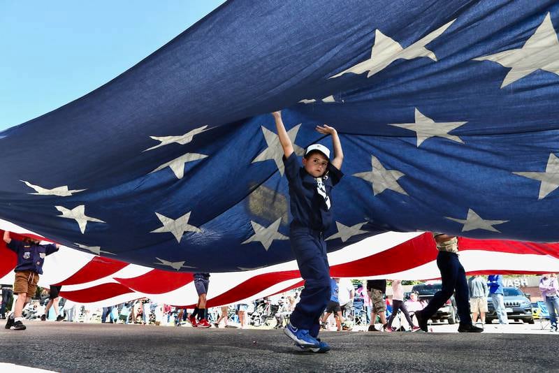 A kid holds up an American Flag as it travels down Main Street during the Homestead Festival on Saturday, Sept. 7,, 2024 in Princeton.