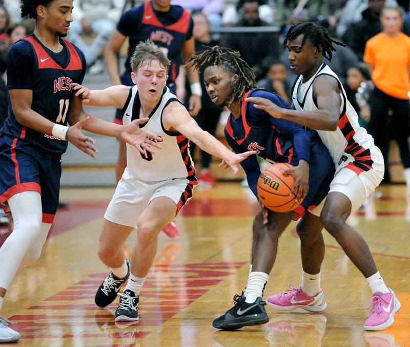 Bolingbrook defenders Trey Brost (0) and DJ Strong (right) trap and strip the ball from West Aurora's Donta'e Woods during a class 4A regional championship basketball game at Yorkville High School on Friday, Feb. 23, 2024.